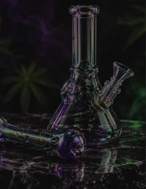 Glass beaker bong and hand pipe on dark marble