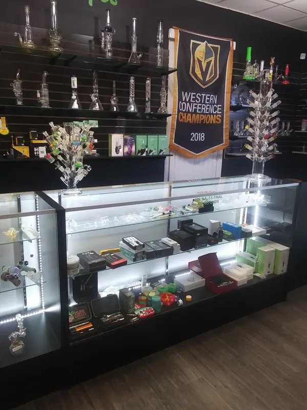 Water pipes on the wall above a lit display case of dab rigs, vaporizers and accessories